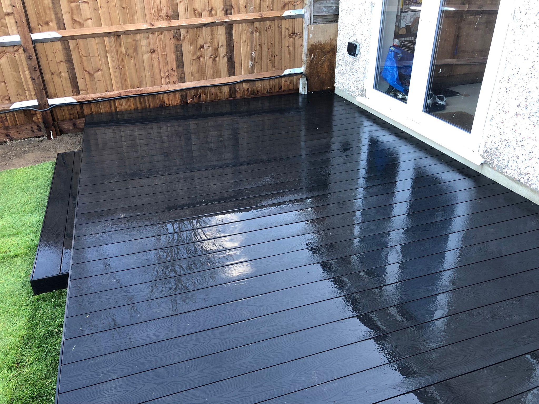 Black composite decking beside new artificial grass, Surrey