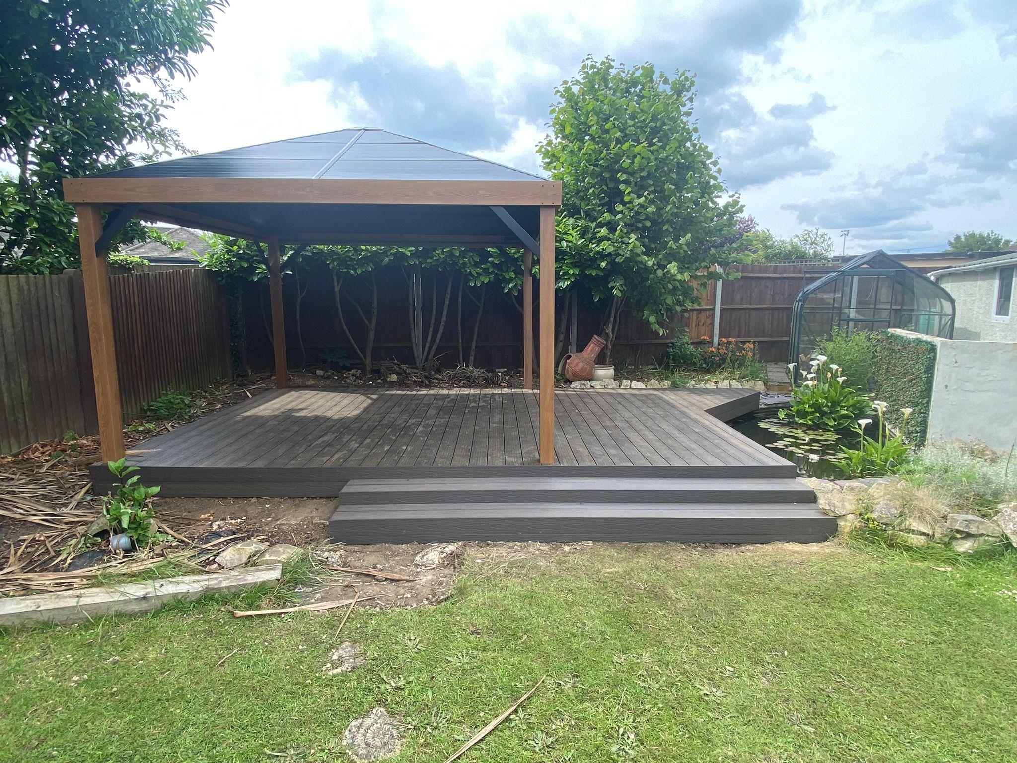 Composite decking with gazebo structure beside garden pond, Surrey