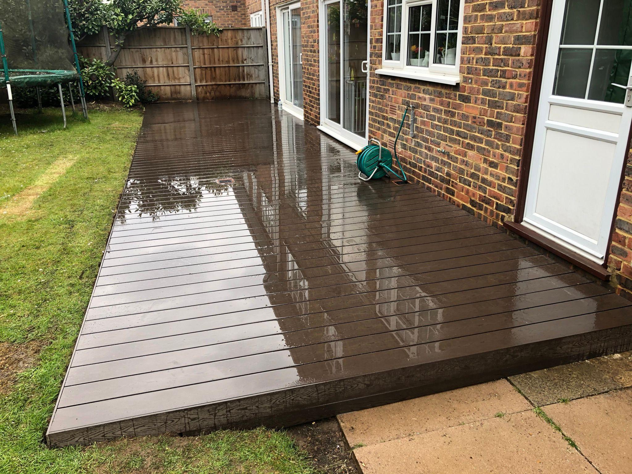 Dark chocolate composite decking in rear garden at brick house, Surrey