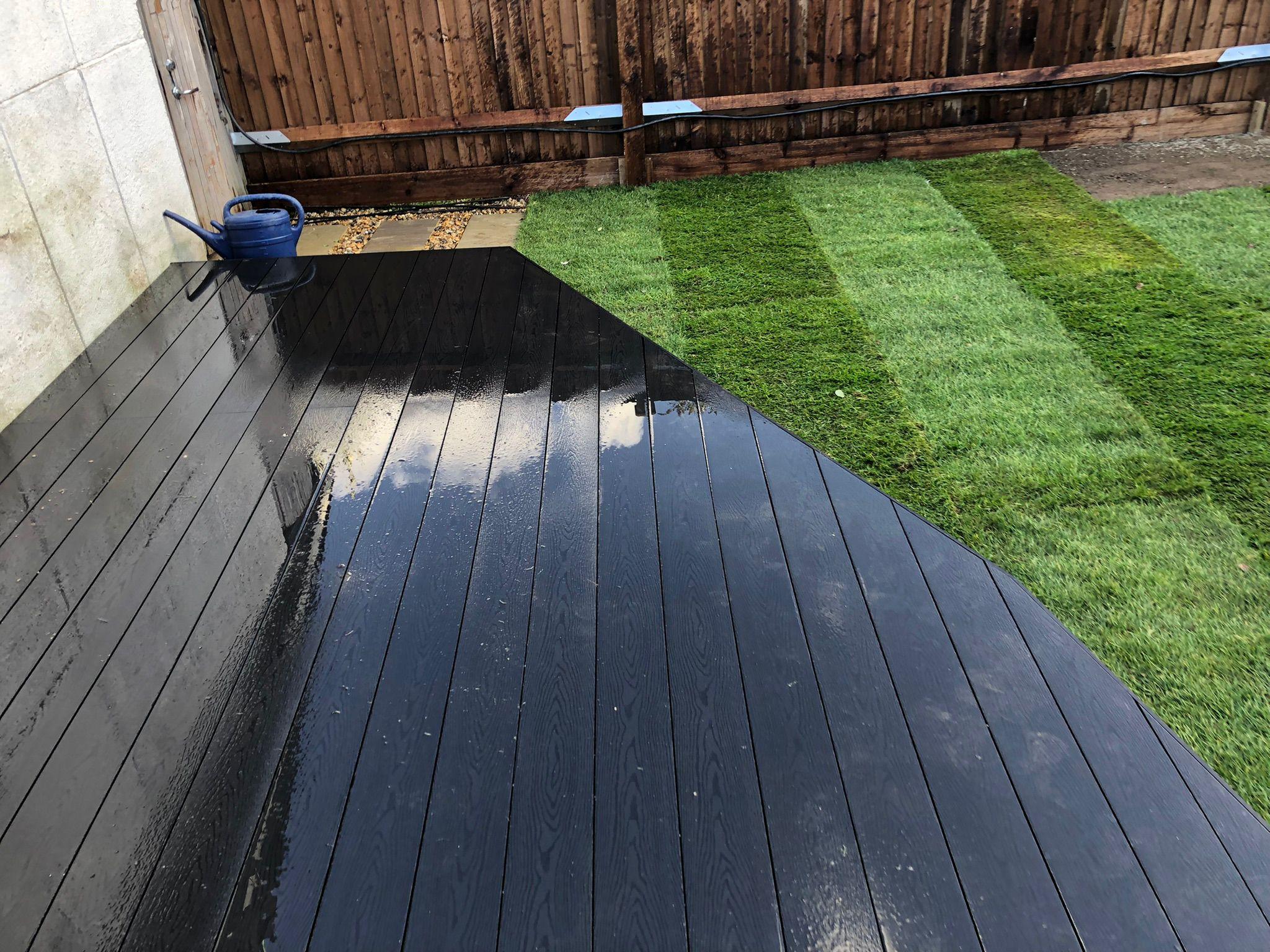 Dark composite decking beside new turf lawn, Surrey