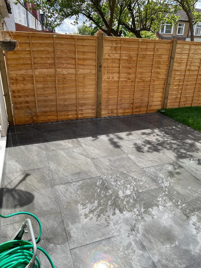 Dark grey porcelain patio in rear garden with close-board fence, Surrey