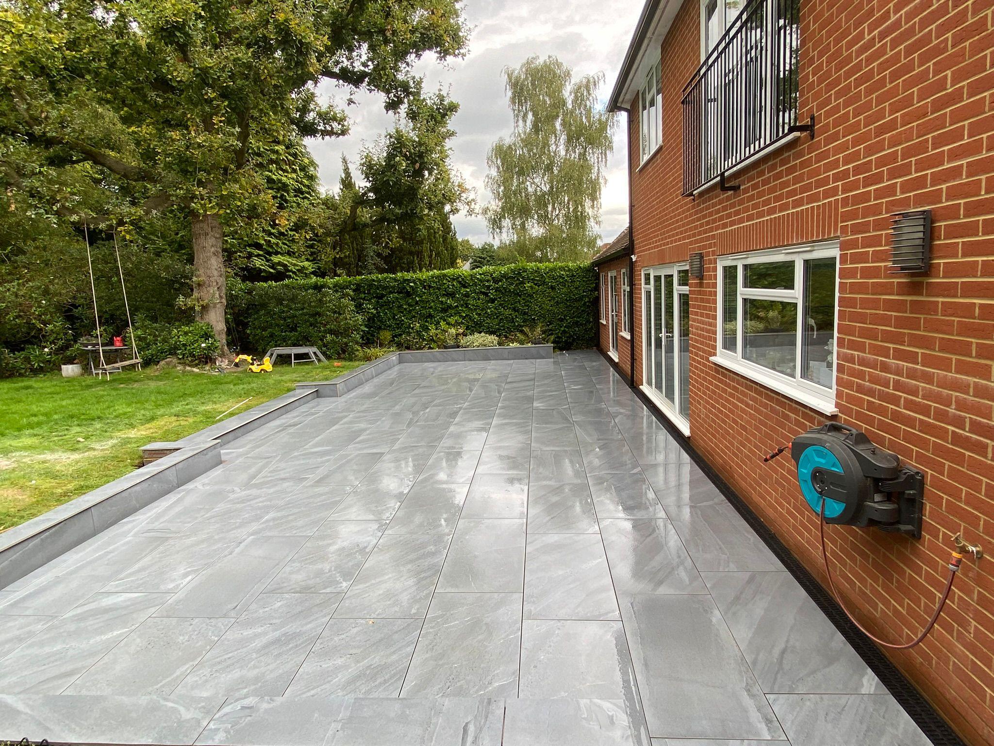 Dark grey porcelain patio side return at brick house, Surrey