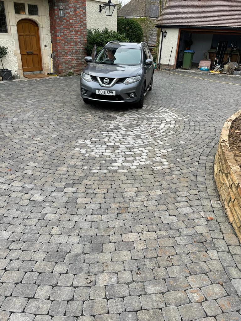 Granite cobblestone sett driveway with circular pattern and parked car, Surrey
