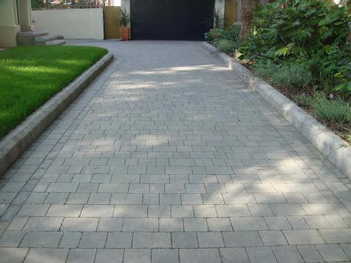 Grey cobblestone sett driveway with lawn edging and garage door, Surrey