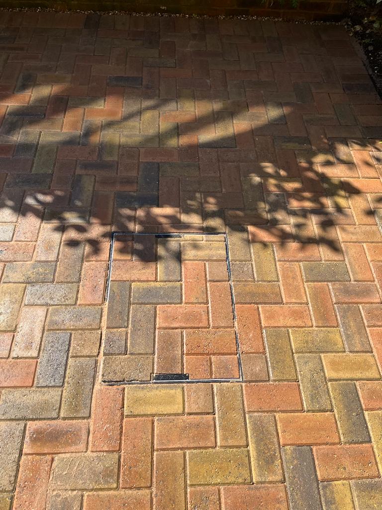 Herringbone block paving close-up with manhole cover, Surrey