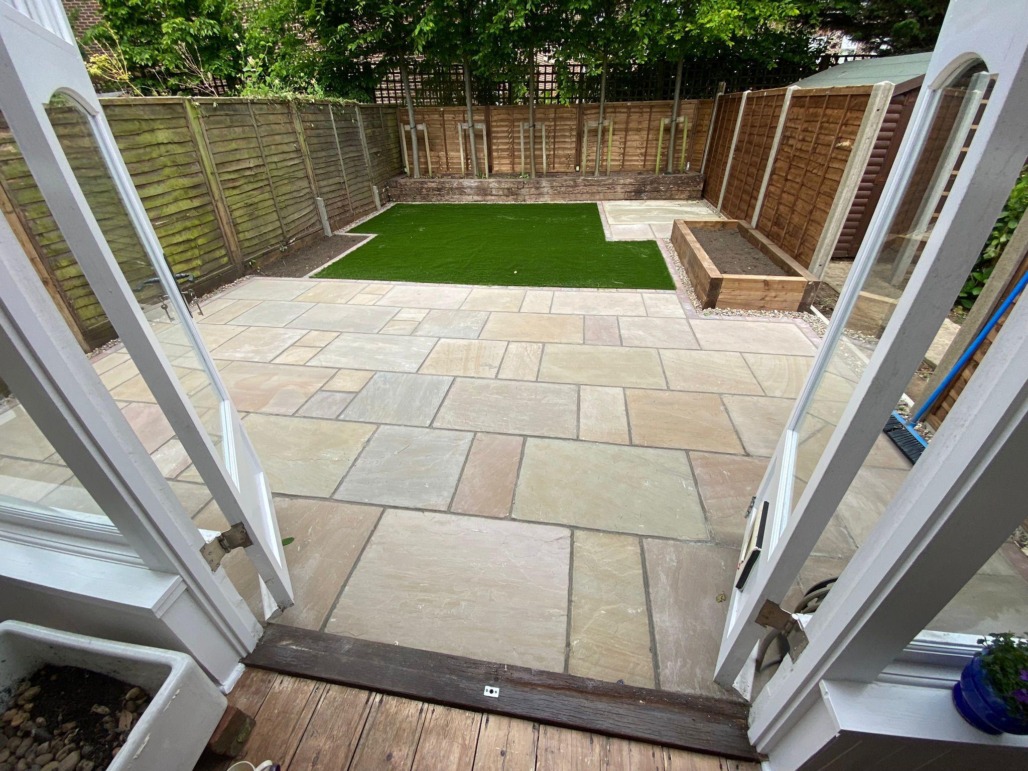Indian sandstone patio with artificial grass and raised planter, Surrey