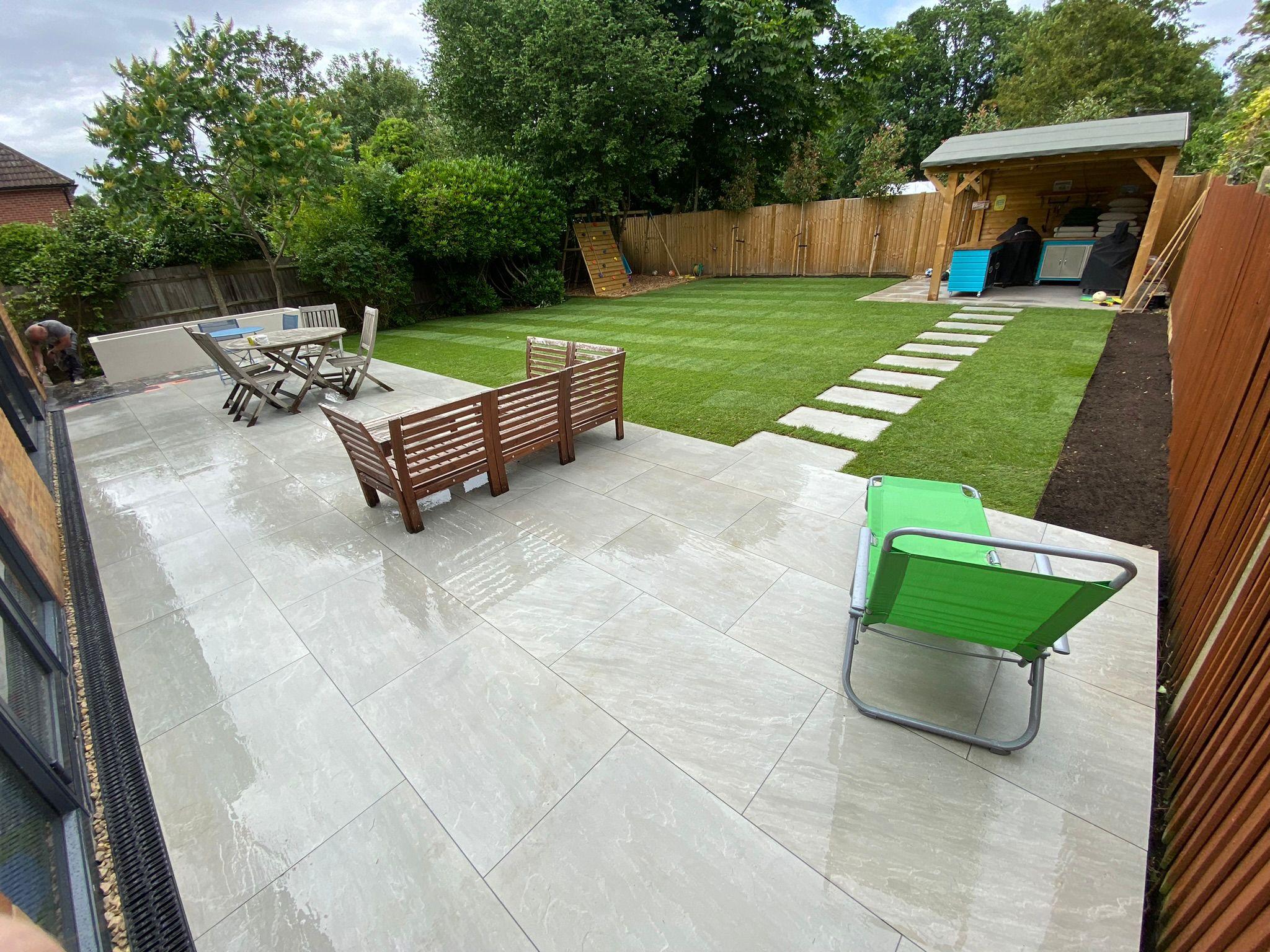 Grey porcelain patio with outdoor furniture and new turf lawn, Surrey