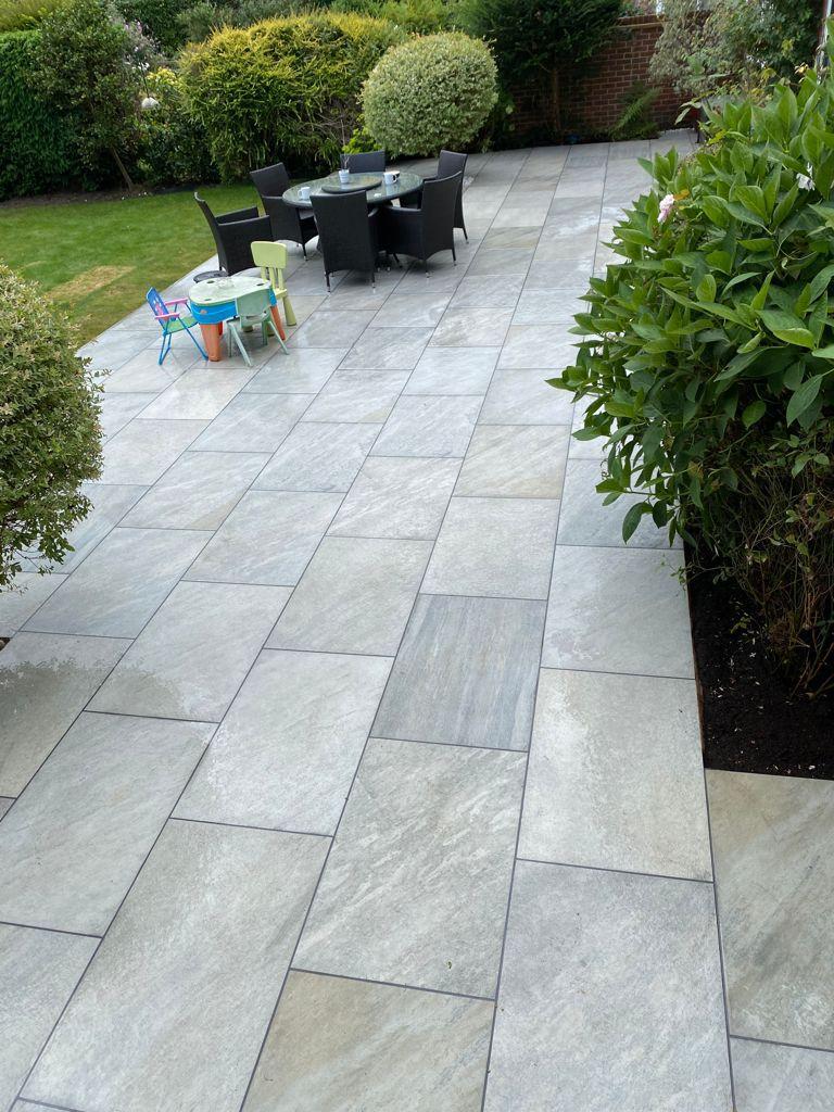 Light grey porcelain patio with dining furniture and lawn, Surrey