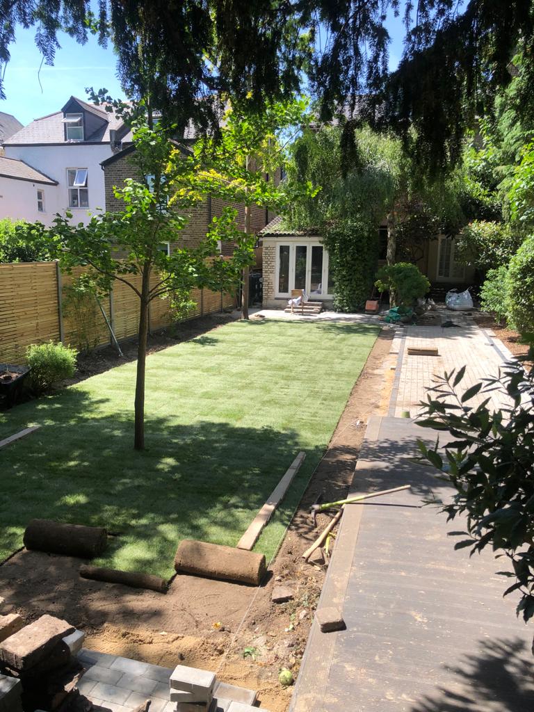 New turf lawn being laid with block paving path aerial view, Surrey