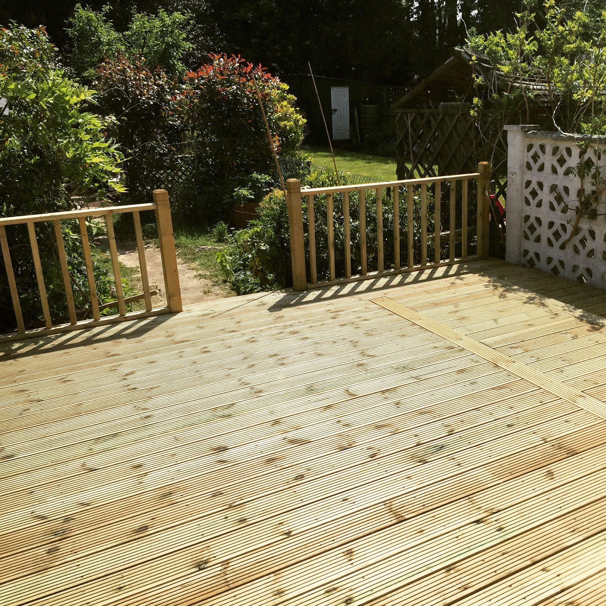 Raised timber decking with balustrade railing in cottage garden, Surrey